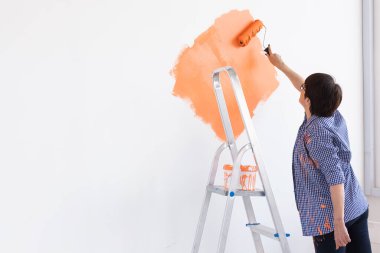 Yeni dairesinde duvar boyayan orta yaşlı güzel bir kadın. Yenileme ve dekorasyon konsepti. Boşluğu kopyala.