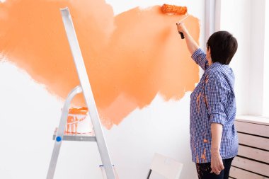 Evin içinde paten yapan orta yaşlı güzel bir kadın. Dekorasyon, yenileme, apartman onarımı ve ferahlatıcı konsept.