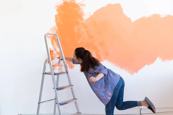 Ristrutturazione, ristrutturazione e concetto di riparazione - Allegro muro di pittura donna in una nuova casa. — Foto Stock