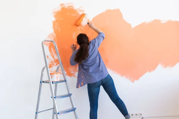 Yeni dairesinde duvar boyayan mutlu genç bir kadın. Yenileme, dekorasyon ve onarım konsepti. — Stok fotoğraf