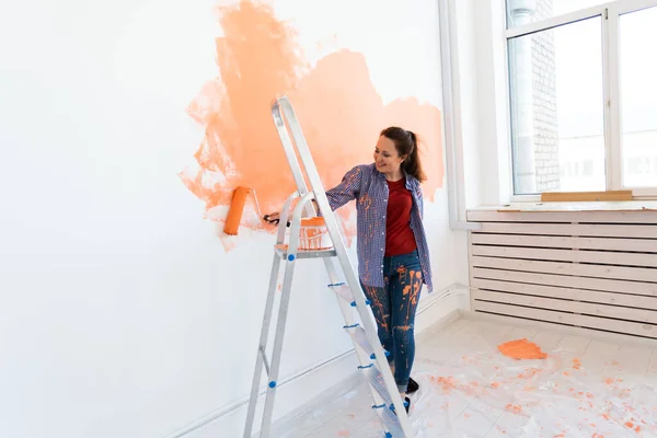 Ristrutturazione, ristrutturazione e concetto di riparazione - Allegro muro di pittura donna in una nuova casa. — Foto Stock