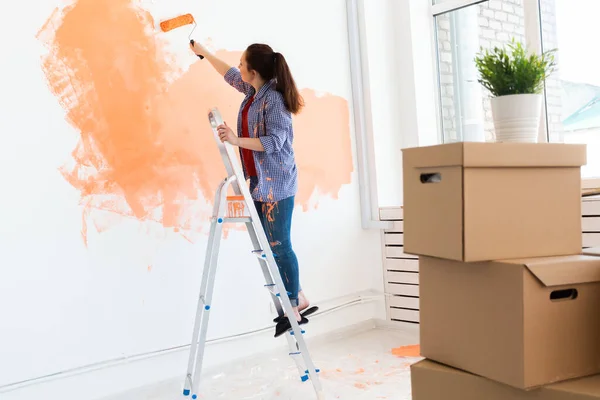 Donna sorridente pittura parete interna della casa. Concetto di ristrutturazione, riparazione e ridecorazione. — Foto Stock