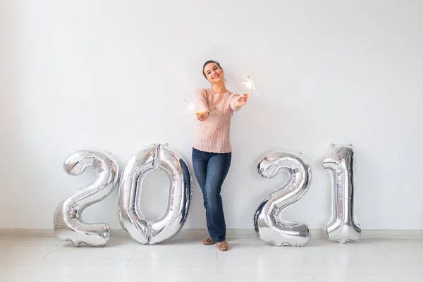 Celebración de Año Nuevo y concepto de fiesta - Mujer joven feliz con brillantes cerca de plata 2021 globos sobre fondo blanco. — Foto de Stock