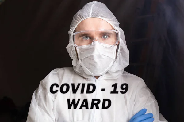 Man in protective suit and in protective medical mask showing stop gesture. Epidemiologist portrait. Stop coronavirus or covid-19 and the pandemic. Stay home. Quarantine concept.