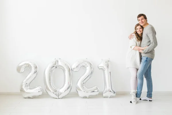 Dovolená, slavnostní a party koncept - Šťastný milující pár drží stříbrné 2021 balónky na bílém pozadí. Novoroční oslava. — Stock fotografie