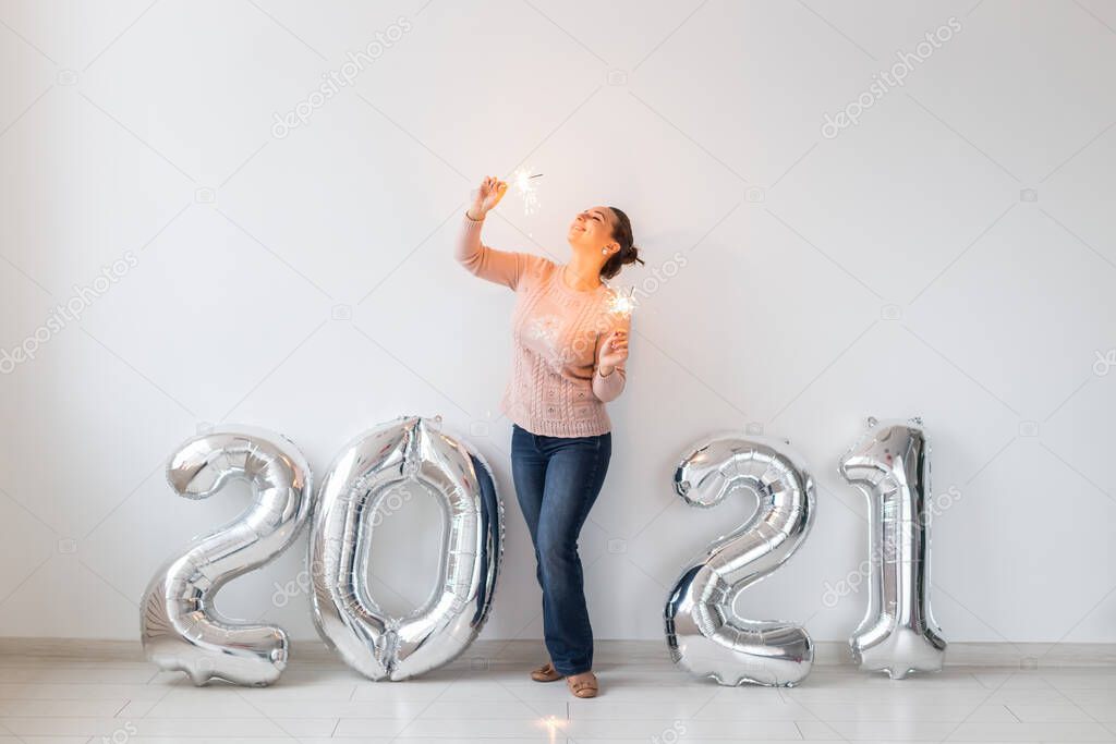 New Year celebration and party concept - Happy young woman with sparklers near silver 2021 balloons on white background.