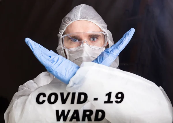 Man in protective suit and in protective medical mask showing stop gesture. Epidemiologist show stop palm. Stop coronavirus or covid-19 and the pandemic. Stay home. Quarantine concept.