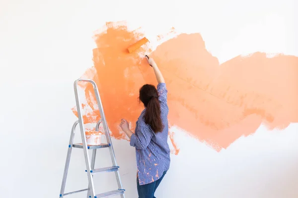 Bella donna che dipinge muro. Concetto di ristrutturazione, ridecorazione e riparazione. — Foto Stock