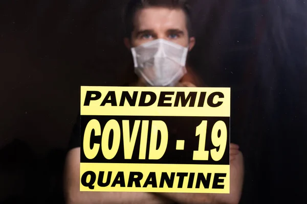 Coronavirus, quarantaine, covid-19 en pandemie concept. Droevige en zieke man van het corona virus die door het raam kijkt. Blijf thuis.. — Stockfoto