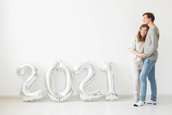 Γιορτές, εορταστική και κόμμα έννοια - Ευτυχισμένο ζευγάρι αγάπη κατέχει ασημένια μπαλόνια 2021 σε λευκό φόντο. Πρωτοχρονιά εορτασμού. — Φωτογραφία Αρχείου