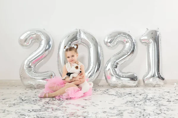 New year, holidays and celebration concept - Little child girl sitting near with numbers balloons 2021