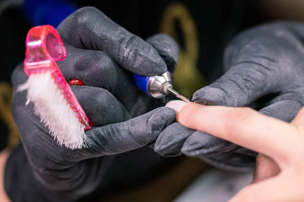 Kadın güzellik salonunda elektrikli tırnak matkabı kullanıyor. Manikür işlemini detaylıca yapıyor. Jel cilası yakın çekim konsepti. — Stok fotoğraf