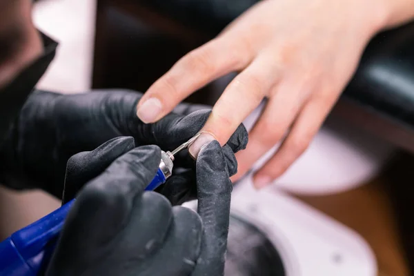 Manicurista utilizzare lima elettrica trapano nel salone di bellezza. Perfetta manicure unghie processo da vicino con scoppiare detriti volanti. — Foto Stock