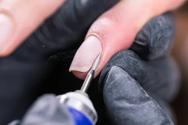 Manikiurzystka używa elektrycznego wiertarki do paznokci w salonie piękności. idealny paznokcie manicure proces zbliżenie z wybuch latające gruzy. — Zdjęcie stockowe