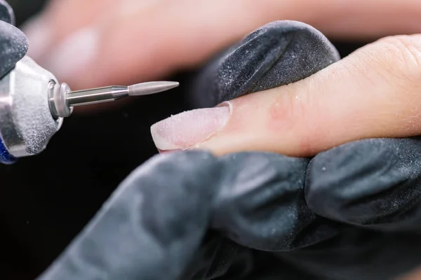 Manicurista utilizzare lima elettrica trapano nel salone di bellezza. Perfetta manicure unghie processo da vicino con scoppiare detriti volanti. — Foto Stock