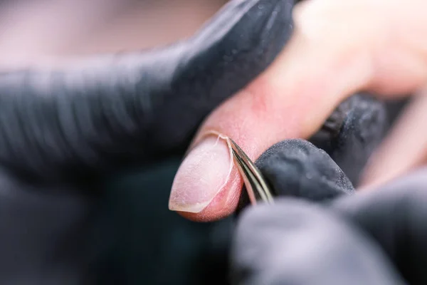 Маникюрша использует электрическую дрель для ногтей в салоне красоты. Идеальный процесс маникюра ногтей близко с разрывом летающих обломков. — стоковое фото