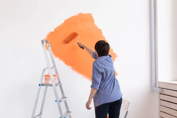 Mujer de mediana edad pintando las paredes de un nuevo hogar. Concepto de renovación, reparación y redecoración. — Foto de Stock