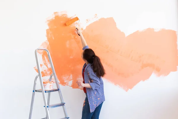 Repair in the apartment. Happy woman paints the wall with paint. — Stock Photo, Image