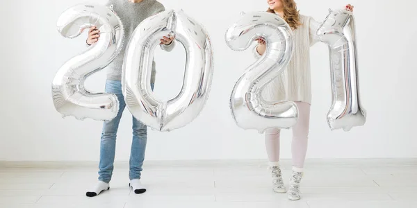 Vacaciones, fiesta y concepto de fiesta - Feliz pareja amorosa sostiene globos de plata 2021 sobre fondo blanco. Celebración de Año Nuevo. — Foto de Stock