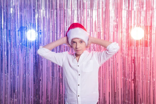 Julen. Tonårspojke med jultomten hatt över glänsande festlig bakgrund. Julhelg koncept. — Stockfoto