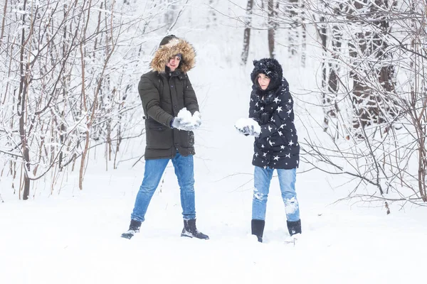 Amor, relacionamento, estação e conceito de amizade - homem e mulher se divertindo e brincando com a neve na floresta de inverno — Fotografia de Stock