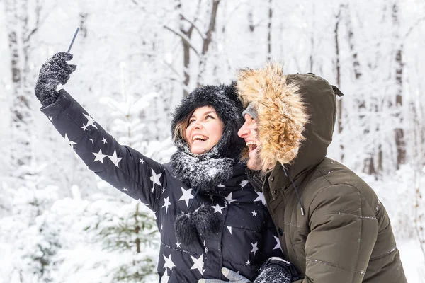 Technologie i koncepcja relacji - Szczęśliwa uśmiechnięta para robi selfie w zimowym lesie na zewnątrz — Zdjęcie stockowe