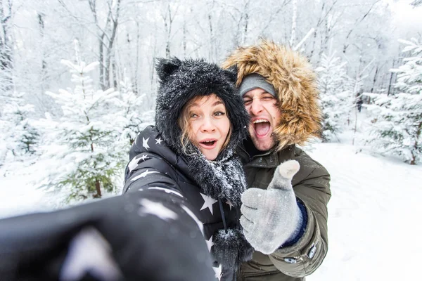 Sezon i koncepcja związku - śmieszne para biorąc selfie w okresie zimowym — Zdjęcie stockowe