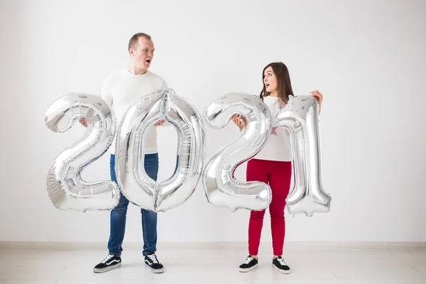 Nuevo 2021 Año viene concepto - Feliz joven hombre y mujer están sosteniendo números de color plata en el interior. — Foto de Stock
