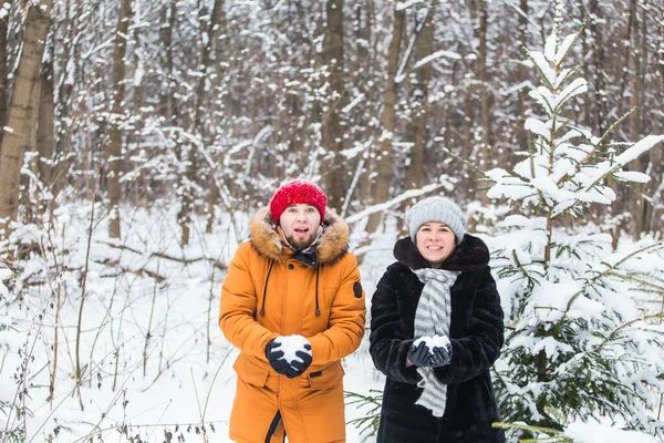 Amour, saison, amitié et concept de personnes - jeune homme et femme heureux s'amuser et jouer avec la neige dans la forêt d'hiver — Photo