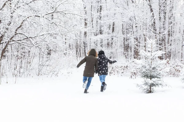 Un jeune et beau couple s'amuse dans le parc enneigé, courant et se tenant la main. Concept de Saint-Valentin. Saison d'hiver. — Photo