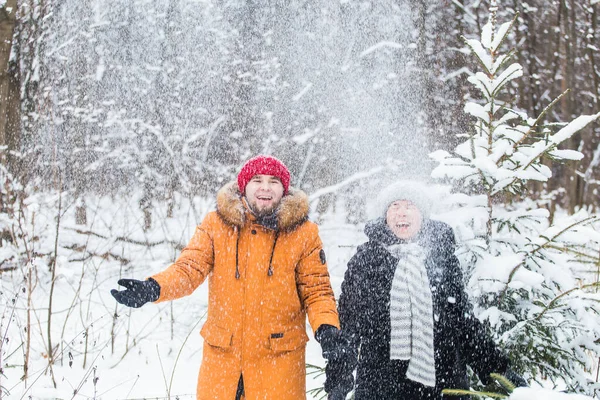 Amour, saison, amitié et concept de personnes - jeune homme et femme heureux s'amuser et jouer avec la neige dans la forêt d'hiver — Photo