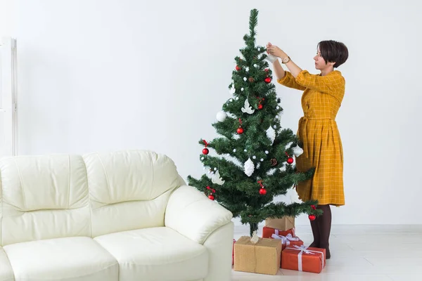 Schöne junge Frau schmückt einen Weihnachtsbaum. Konzept für Feiertage und Feiern. — Stockfoto