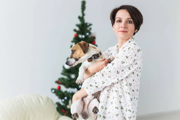 Joyeux jeune femme avec beau chien dans le salon avec arbre de Noël. Concept de vacances. — Photo