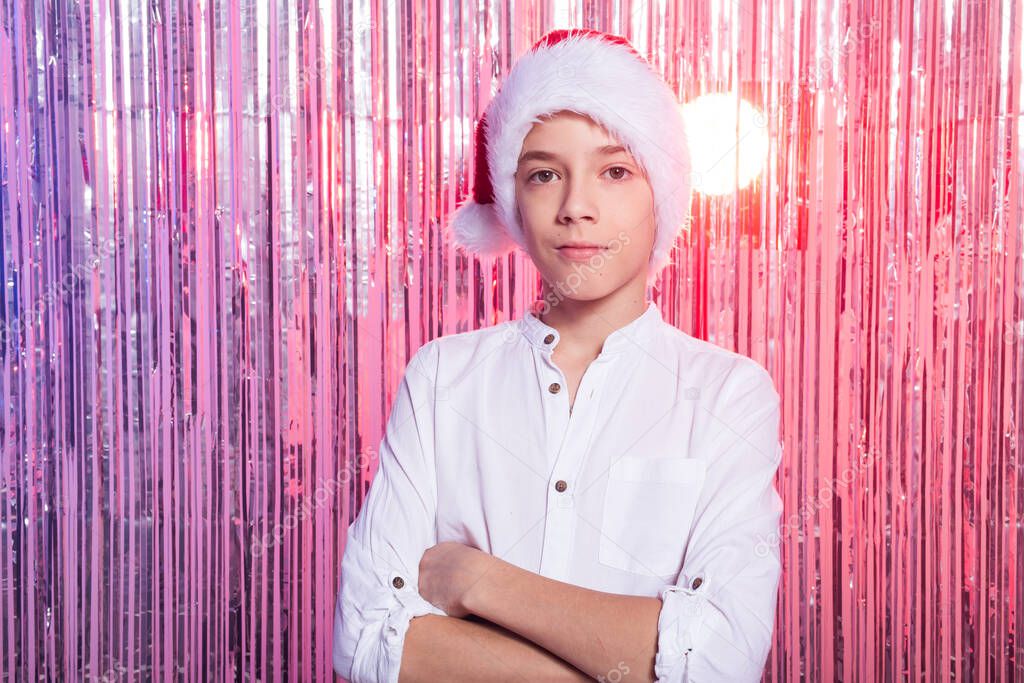 Christmas time. Teen boy with Santa Claus Hat over shiny festive background. Christmas holidays concept.