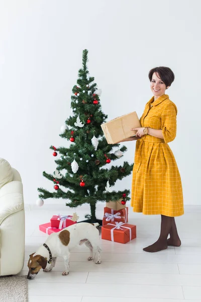 Ευτυχισμένη νεαρή γυναίκα με υπέροχο κουτάκι για το άνοιγμα του σκύλου κάτω από το χριστουγεννιάτικο δέντρο. Έννοια διακοπών. — Φωτογραφία Αρχείου
