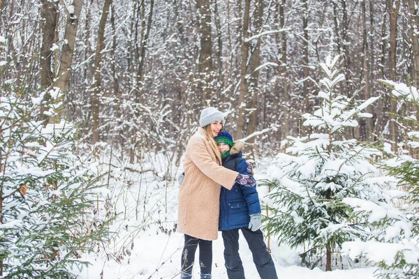 Concept amusant et de saison - Bonne mère et son fils s'amuser et jouer avec la neige dans la forêt d'hiver — Photo