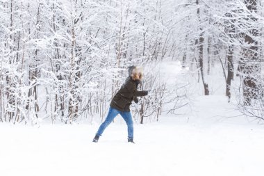 Yaşam tarzı, sezon ve eğlence konsepti - kış parkında kartopu oynayan komik çift