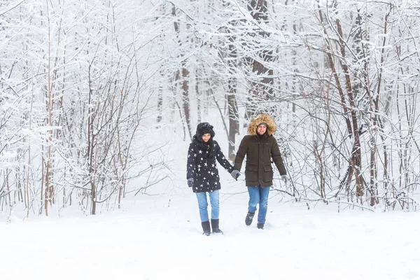 Jeune couple marchant dans un parc enneigé. Saison d'hiver. — Photo