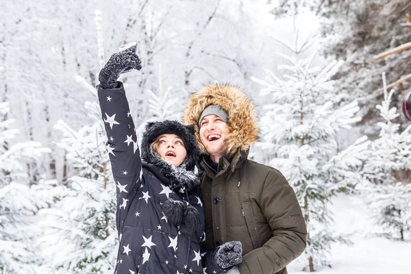 Technologies et concept de relation - Couple souriant heureux prenant un selfie dans une forêt d'hiver à l'extérieur — Photo