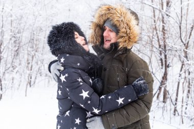 Genç aşık çift karlı ormanda eğleniyor. Aktif kış tatili.