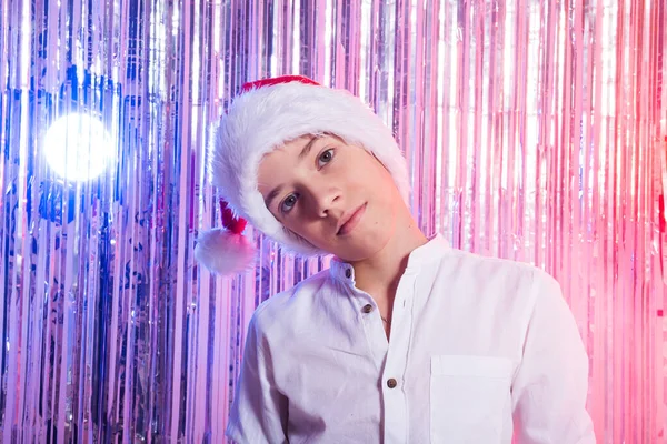 En Navidad. Niño adolescente con sombrero de Papá Noel sobre fondo festivo brillante. concepto de vacaciones de Navidad. —  Fotos de Stock