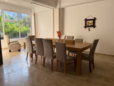 Ahşap masalı ve döşeli sandalyeli yemek odası. Konukseverlik, iç tasarım ve sosyal yaşam tarzı atmosferi, sakin ve modern alan toplanmak için.