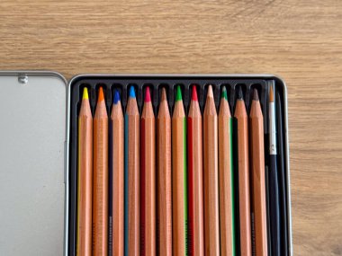 Masadaki metal bir kutuda düzgünce düzenlenmiş renkli ahşap kalemler. Günlük hayatta çizim ve resim yapmak için yaratıcılık, öğrenme ve sanatsal araçlar