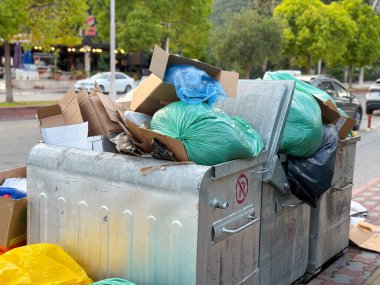 Plastik torbalar ve kartonla dolu bir çöp konteynırı. Kentsel atık, kirlilik ve çevre sorunu.