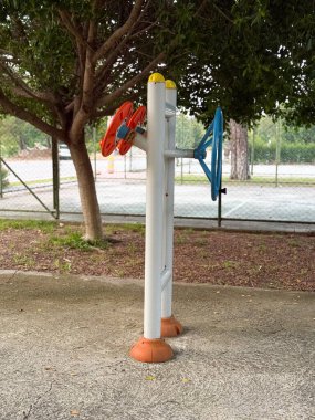Parktaki tenis kortunun yanında bulunan açık hava eğitim makinesi. Spor, hareket ve sağlık günlük yaşam tarzında toplumsal etkinlik, güç ve sağlık gösteriyor.
