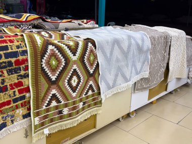Çeşitli geometrik tasarımları olan bir pazarda sergilenen bir sıra desenli halı. Gelenek, zanaat ve tüketici seçimi tekstil sanatı, mobilya ve kültür mirası yoluyla yansıtılıyor