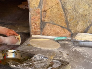 Elleri un kaplı bir yüzeyde sebzeli ekmek hazırlıyor. Geleneksel aşçılık, mutfak ve gastronomi el yapımı ekmek, pişirme ve aşçılık ile temsil edilir.