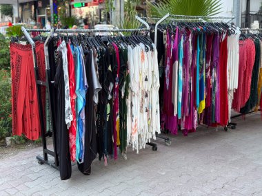 Sokak pazarında renkli elbiselerle sergilenen elbise askılığı. Açık şehir ticaret ortamında perakende, alışveriş ve moda kavramı