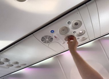 Erkek el, uçak kabinindeki havalandırmayı ayarlıyor. Yolcu konforu, havacılık teknolojisi ve seyahat deneyimi