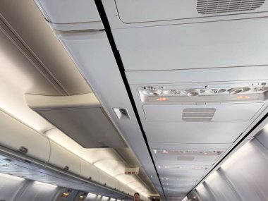 Yolcu koltuklarının üzerinde havalandırma delikleri, tabelalar ve kompartımanlar olan bir uçak kabini tavanı. Seyahat, havacılık ve konfor ve güvenlik için uçak iç mekanlarının teknik tasarımı